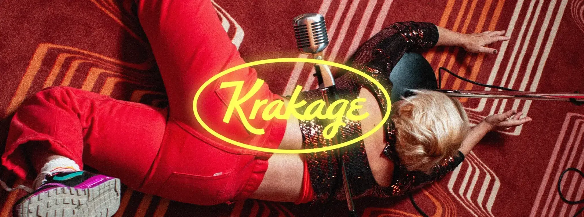 Chanteuse allongée sur un tapis rouge avec micro et logo néon Krakage